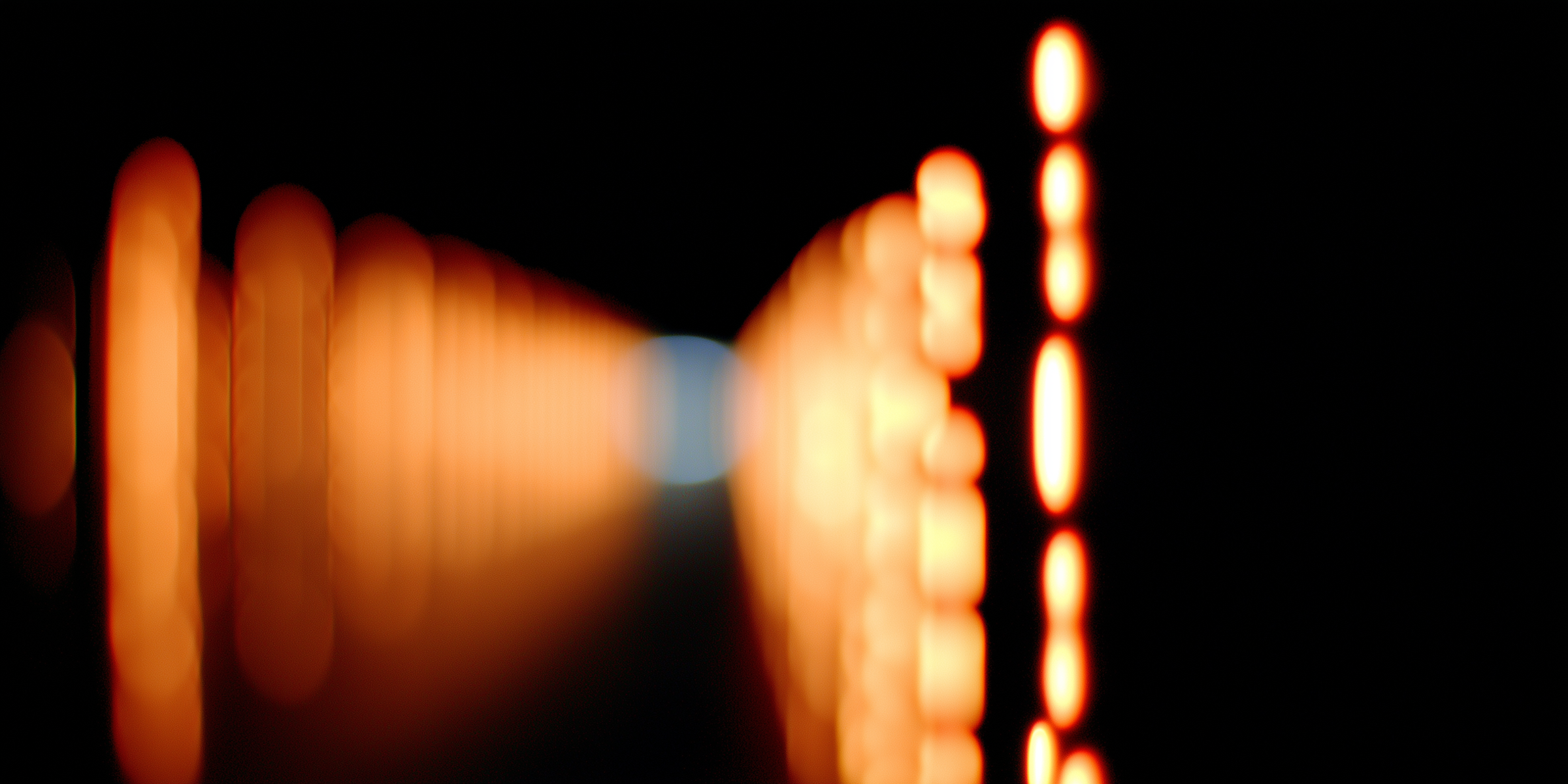 Abstract blurred tunnel of orange and white light signals against a black background, creating a distorted forward-view effect.